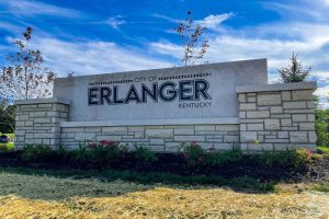City of Erlanger, Kentucky sign mounted on a stone wall with a landscaped flower bed in front.