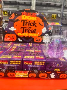 Halloween shelf display with Trick or Treat Nice Cube boxes, orange pumpkins, bats and ghosts; a purple ghost toy in plastic wrap.