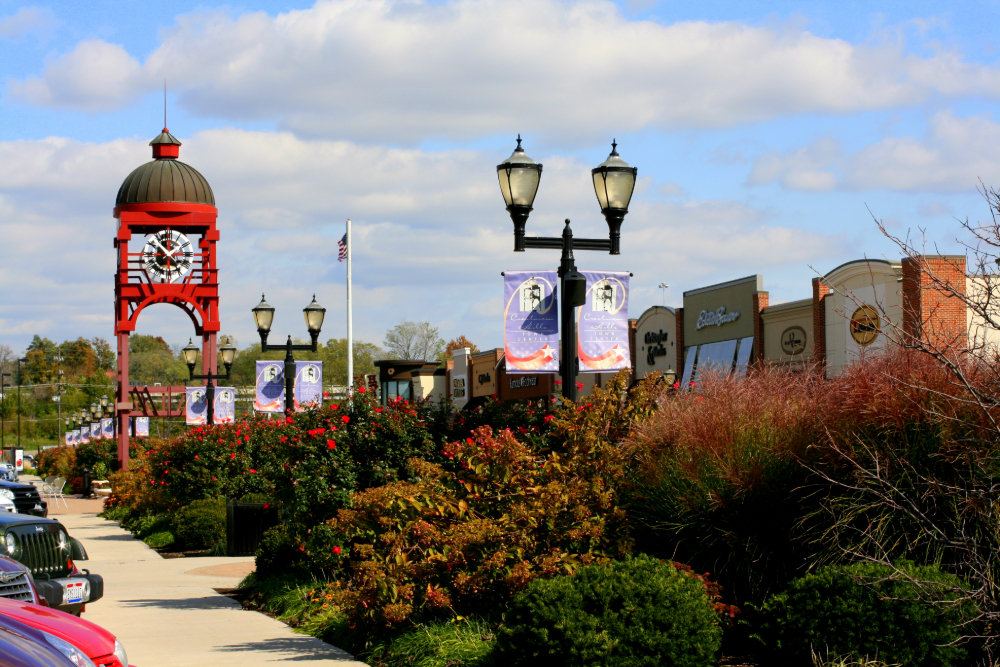 Crestview-Hills-Kentucky | Route 17 Express Red clock tower and street lamps lining a suburban shopping district with banners and storefronts under a blue sky.